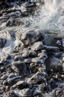 Şelalenin dibindeki detaylar. Taşlar, kaya ve akan su, kısmen büyük buz parçalarına dönüşmüş. Kuzeydoğu İzlanda 'da sonbahar, Rjukandafoss.