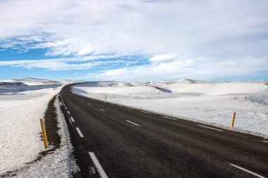Mavi gökyüzü ve beyaz bulutlarla güzel bir sonbahar günü. Yolun kalitesi ve lastikler sadece beyaz güzelliğin tadını çıkarmaya yarar. Kuzey-Doğu İzlanda.