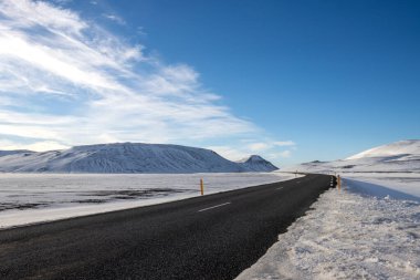 Mavi gökyüzü ve beyaz bulutlarla güzel bir sonbahar günü. Yolun kalitesi ve lastikler sadece beyaz güzelliğin tadını çıkarmaya yarar. Kuzey-Doğu İzlanda.