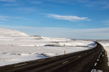Mavi gökyüzü ve beyaz bulutlarla güzel bir sonbahar günü. Yolun kalitesi ve lastikler sadece beyaz güzelliğin tadını çıkarmaya yarar. Kuzey-Doğu İzlanda.