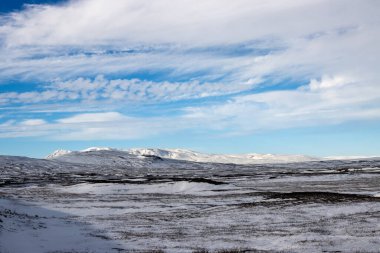 Mavi gökyüzü ve beyaz bulutlarla güzel bir sonbahar günü. Dalgalar ve küçük tepelerle kaplanmış taze kar. Kuzey-Doğu İzlanda.