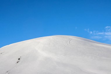 Mavi gökyüzü ve beyaz bulutlarla güzel bir sonbahar günü. Dalgalar ve küçük tepelerle kaplanmış taze kar. Kuzey-Doğu İzlanda.