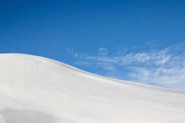 Mavi gökyüzü ve beyaz bulutlarla güzel bir sonbahar günü. Dalgalar ve küçük tepelerle kaplanmış taze kar. Kuzey-Doğu İzlanda.