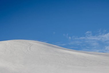 Mavi gökyüzü ve beyaz bulutlarla güzel bir sonbahar günü. Dalgalar ve küçük tepelerle kaplanmış taze kar. Kuzey-Doğu İzlanda.