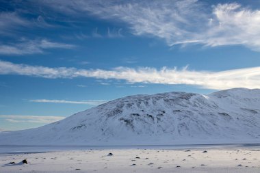 Mavi gökyüzü ve beyaz bulutlarla güzel bir sonbahar günü. Dalgalar ve küçük tepelerle kaplanmış taze kar. Kuzey-Doğu İzlanda.