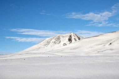Mavi gökyüzü ve beyaz bulutlarla güzel bir sonbahar günü. Dalgalar ve küçük tepelerle kaplanmış taze kar. Kuzey-Doğu İzlanda.