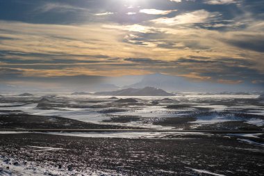 Gayzerlerin çok sık görüldüğü ve jeotermal aktivitelerin kar üzerindeki çözülmemiş çizgilerde de görülebildiği bölge. Kuzey-Merkez Bölgesi Myvatn, İzlanda 'da gün batımı.