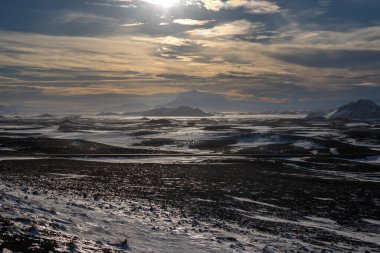 Gayzerlerin çok sık görüldüğü ve jeotermal aktivitelerin kar üzerindeki çözülmemiş çizgilerde de görülebildiği bölge. Kuzey-Merkez Bölgesi Myvatn, İzlanda 'da gün batımı.