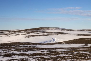 Gayzerlerin çok sık görüldüğü ve jeotermal aktivitelerin kar üzerindeki çözülmemiş çizgilerde de görülebildiği bölge. Kuzey-Merkez Bölgesi Myvatn, İzlanda 'da gün batımı.