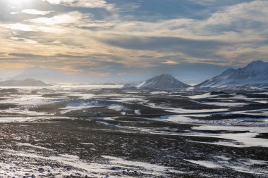 Gayzerlerin çok sık görüldüğü ve jeotermal aktivitelerin kar üzerindeki çözülmemiş çizgilerde de görülebildiği bölge. Kuzey-Merkez Bölgesi Myvatn, İzlanda 'da gün batımı.