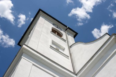 All Saints Kilisesi, erken barok tarzında inşa edilmiş. Mükemmel koşullarda beyaz cephe, tüm kilise gibi. Parlak mavi gökyüzü. Dlouhomilov, Moravya, Çek Cumhuriyeti.