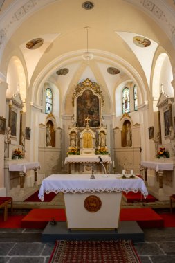 All Saints kilisesinin sunağı. Kemer tavanı, vitamin pencereleri. Resimler ve heykeller. Kırmızı halı. Güneşli bir günde güzel bir ışık. Dlouhomilov, Moravya, Çek Cumhuriyeti.