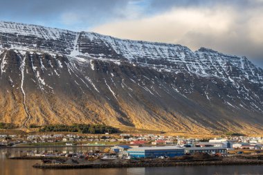 Mavi gökyüzü ve bulutlarla gün batımının başlangıcı. Fiyortta Atlantik Okyanusu 'nun Suyu. Sonbaharda biraz kar yağan görkemli tepeler. Westfjords, Isafjordur, İzlanda Bölgesi.
