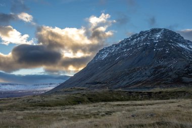 Mavi gökyüzü ve bulutlarla gün batımının başlangıcı. Sonbaharda biraz kar yağan görkemli tepeler. Westfjords, Isafjordur, İzlanda Bölgesi.