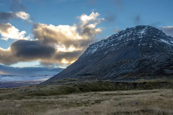 Mavi gökyüzü ve bulutlarla gün batımının başlangıcı. Sonbaharda biraz kar yağan görkemli tepeler. Westfjords, Isafjordur, İzlanda Bölgesi.