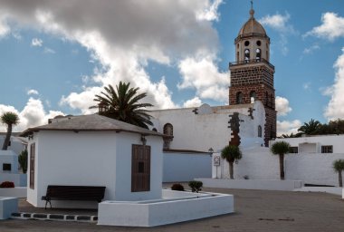 Kış öğleden sonraları geleneksel beyaz mimari. Iglesia de Nuestra Sinyora de Guadalupe kilisesinin yüksek kulesi. Beyaz bulutlu mavi gökyüzü. Teguise, Lanzarote, Kanarya Adaları, İspanya.