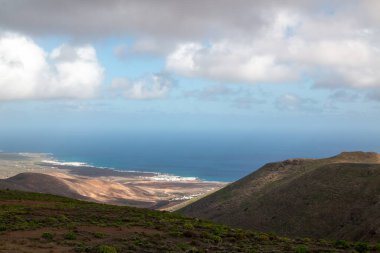 Adanın kuzeyindeki yüksek kayalıklar Atlantik Okyanusu 'nda. Beyaz bulutlu mavi gökyüzü. Lanzarote, Kanarya Adaları, İspanya.