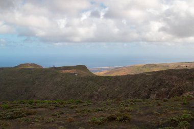 Adanın kuzeyindeki yüksek kayalıklar Atlantik Okyanusu 'nda. Beyaz bulutlu mavi gökyüzü. Lanzarote, Kanarya Adaları, İspanya.
