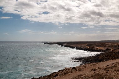 Atlantik Okyanusu kıyısındaki volkanik kayalar. Kışın bulutlu bir gökyüzü. Arrieta, Lanzarote, Kanarya Adaları, İspanya.