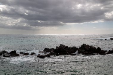 Atlantik Okyanusu kıyısındaki volkanik kayalar. Kışın bulutlu bir gökyüzü. Arrieta, Lanzarote, Kanarya Adaları, İspanya.