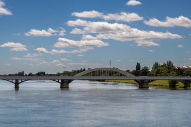 En çok Krajinsky, Vah nehrinin karşısında. Taze çimenler ve nehir kıyısında bir sürü ağaç. Beyaz bulutlu mavi gökyüzü. Piestany, Slovakya.