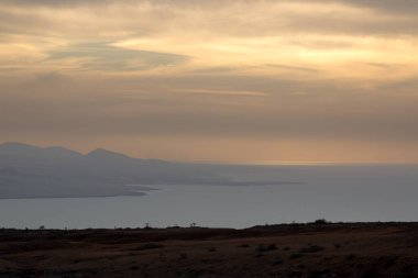 Atlantik okyanusunun sakin suları. Kışın bulutlu bir gökyüzü. Renkli bulutlarla gün batımı. Bakış açısı Miarador del Rio, Lanzarote, Kanarya Adaları, İspanya.