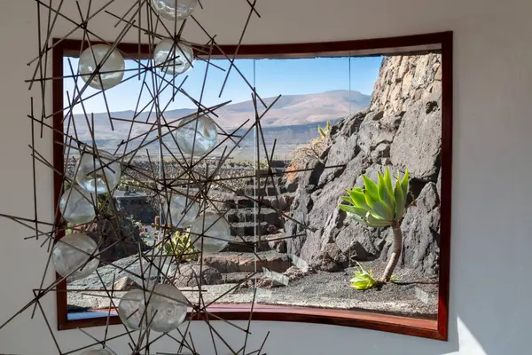 stock image Indoor of a building in a Cactus Park, created by Cesar Manrique. Lamp and a large arch window with a view to the park. Guatiza, Lanzarote, Canary Islands, Spain.