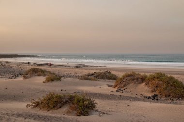 Adanın batı kıyısında kumlu bir plaj var. Sörfçülüğüyle ünlüdür. Kış mevsiminde altın saat. Arka planda dağlar. Caleta de Famara, Lanzarote, Kanarya Adaları, İspanya.