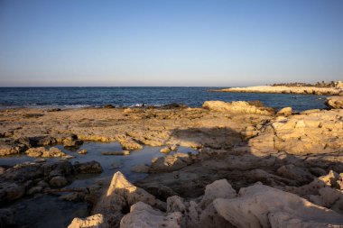 Akdeniz 'in kayalık kıyıları. Sahilin umumi bir parçası. Altın saatin ışığında kayalar. Djerba, Tunus, Afrika.