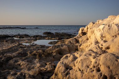 Akdeniz 'in kayalık kıyıları. Sahilin umumi bir parçası. Altın saatin ışığında kayalar. Djerba, Tunus, Afrika.