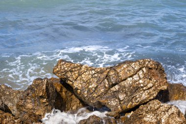 Dokulu kıyı dalgakıranı taşları, İyonik deniz damlaları. Güneşli bir gün. Astrakeri, Kuzey Korfu, Yunanistan.