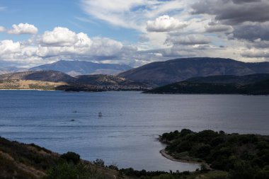 İyonik denizin sakin suları. Arnavutluk 'un dağlarındaki Yunan adasından görüntü. Yazın sonunda yoğun bulutlarla dolu bir gökyüzü. Kuzey Doğu Korfu, Yunanistan.