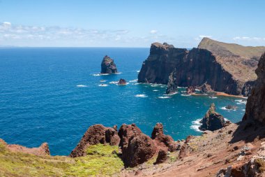 Baharın güneşli bir gününde, Atlantik ve yarımadanın kayalıkları. Beyaz bulutlu mavi gökyüzü. Vulcao Penha de Aquia, Madeira, Portekiz.