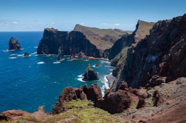 Baharın güneşli bir gününde, Atlantik ve yarımadanın kayalıkları. Beyaz bulutlu mavi gökyüzü. Vulcao Penha de Aquia, Madeira, Portekiz.