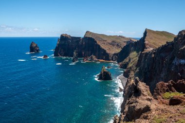 Baharın güneşli bir gününde, Atlantik ve yarımadanın kayalıkları. Beyaz bulutlu mavi gökyüzü. Vulcao Penha de Aquia, Madeira, Portekiz.