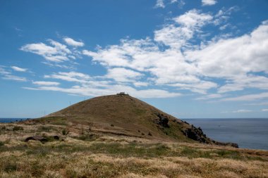 Baharın güneşli bir gününde, Atlantik ve yarımadanın kayalıkları. Beyaz bulutlu mavi gökyüzü. Vulcao Penha de Aquia, Madeira, Portekiz.