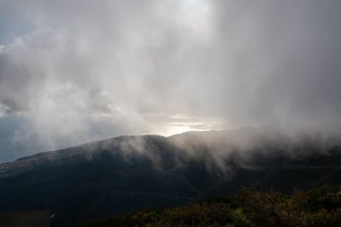 Mountains covered by fresh greenery. Clouds above them during a spring early evening. Risk Calheta, Miraduro do Rabacal, Madeira, Portugal. clipart