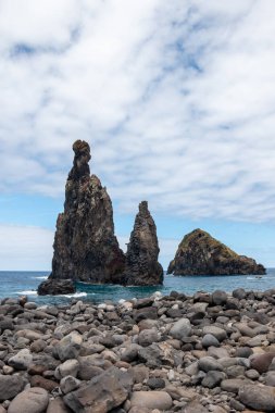 Atlantik Okyanusu 'ndaki volkanik kaya oluşumları, kıyıya yakın. Baharda beyaz bulutlu mavi gökyüzü. Ribeira da Janela, Madeira, Portekiz.