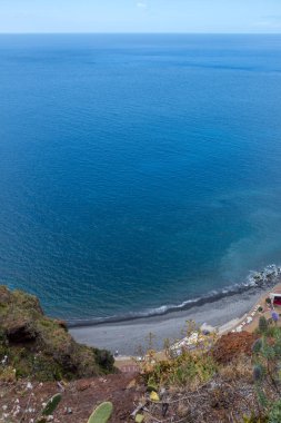 Sahildeki bir dağdan Atlantik 'in sakin sularına bak. Baharda beyaz bulutlu mavi gökyüzü. Canico, Madeira, Portekiz.