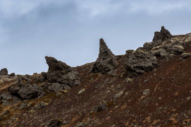 Tepenin kenarındaki kayaların soyut şekilleri. Arka planda bulutlu bir gökyüzü. Snaefellsnes Yarımadası, İzlanda.