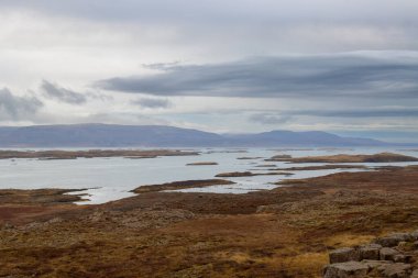 Kuzey Snaefellsnes 'den fiyordun dışındaki küçük adalara (Olafsey, Brokey, Oxney) bakın. Sahilde sonbahar otları, kayalar ve taşlar. Sonbaharda bulutlu bir gökyüzü. Batı İzlanda.