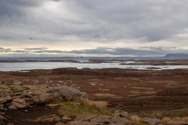 View from north Snaefellsnes on the small islands (Olafsey, Brokey, Oxney) in the out part of fjord. Autumn grass and rocks and stones on the coast. Cloudy sky in the autumn. West Iceland. clipart