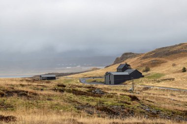 Sonbahar doğası, genel İzlanda mimarisi, siyah evler, yoğun bulutlu gökyüzü ve sis. Kaplıcalı bir yer. Hvammsvik, Batı İzlanda.