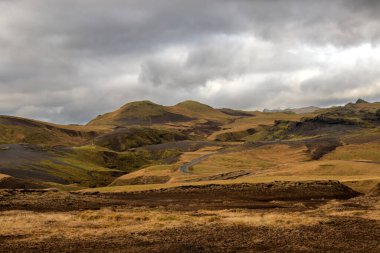 Sonbaharda kadife bir yüzeye sahip olan volkanik kayalar ve dağlar, sarı yosun, liken ve çimenler sayesinde. Beyaz bulutlu mavi gökyüzü. Katla geopark, İzlanda.