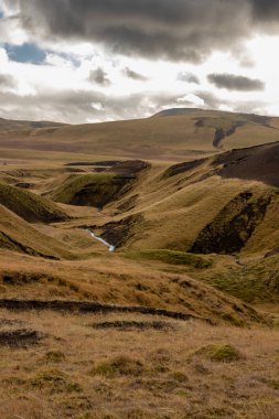 Sonbaharda kadife bir yüzeye sahip olan volkanik kayalar ve dağlar, sarı yosun, liken ve çimenler sayesinde. Beyaz bulutlu mavi gökyüzü. Katla geopark, İzlanda.