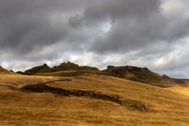 Sonbaharda kadife bir yüzeye sahip olan volkanik kayalar ve dağlar, sarı yosun, liken ve çimenler sayesinde. Beyaz bulutlu mavi gökyüzü. Katla geopark, İzlanda.