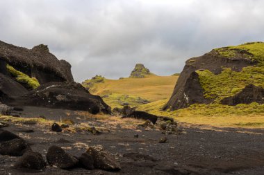 Sonbaharda kadife bir yüzeye sahip olan volkanik kayalar ve dağlar, sarı yosun, liken ve çimenler sayesinde. Beyaz bulutlu mavi gökyüzü. Katla geopark, İzlanda.