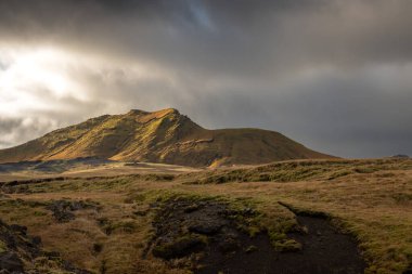 Sonbaharda kadife bir yüzeye sahip olan volkanik kayalar ve dağlar, sarı yosun, liken ve çimenler sayesinde. Beyaz bulutlu mavi gökyüzü. Katla geopark, İzlanda.