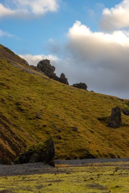 Sonbaharda kadife bir yüzeye sahip olan volkanik kayalar ve dağlar, sarı yosun, liken ve çimenler sayesinde. Beyaz bulutlu mavi gökyüzü. Katla geopark, İzlanda.
