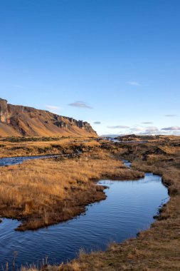 Yosun ve yosunla kaplı bir dağ. Tepesinde yapılandırılmış bir şekil olan volkanik kaya. Sonbaharda güzel güneşli bir gün Güney İzlanda, Kalfafell yakınlarında..